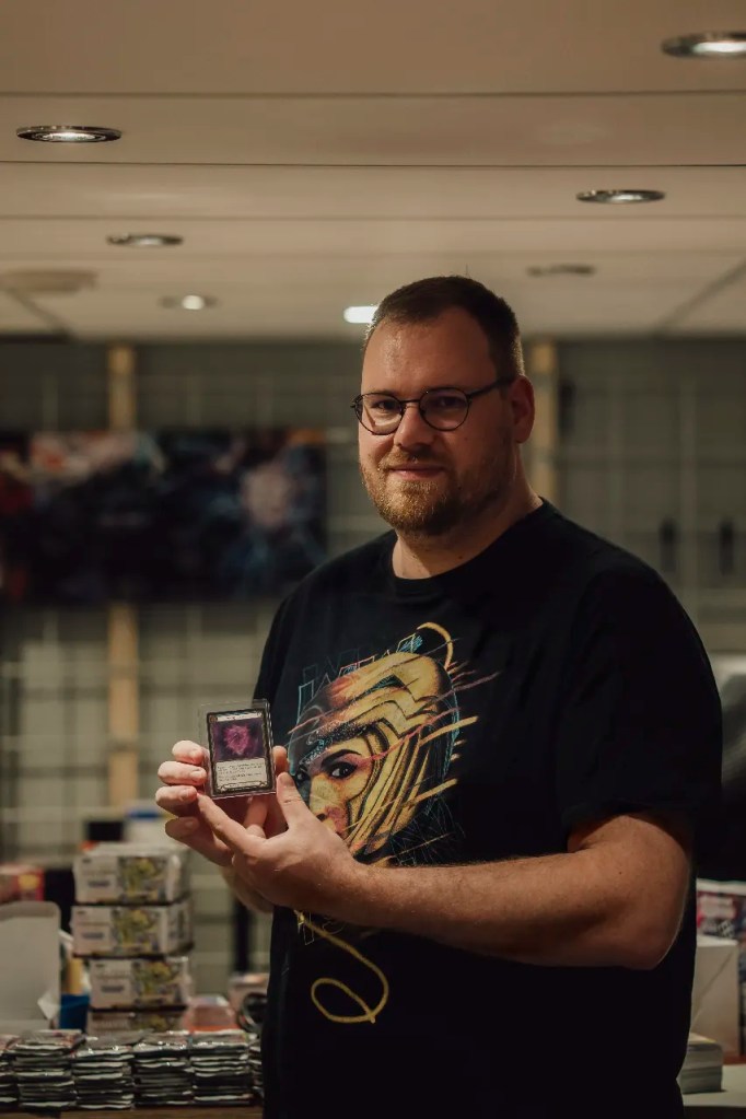 Corné van Dooren holding the Arknight Shard Cold Foil inside Kai of Cards store in Ederveen, Light and Relic provenance project.